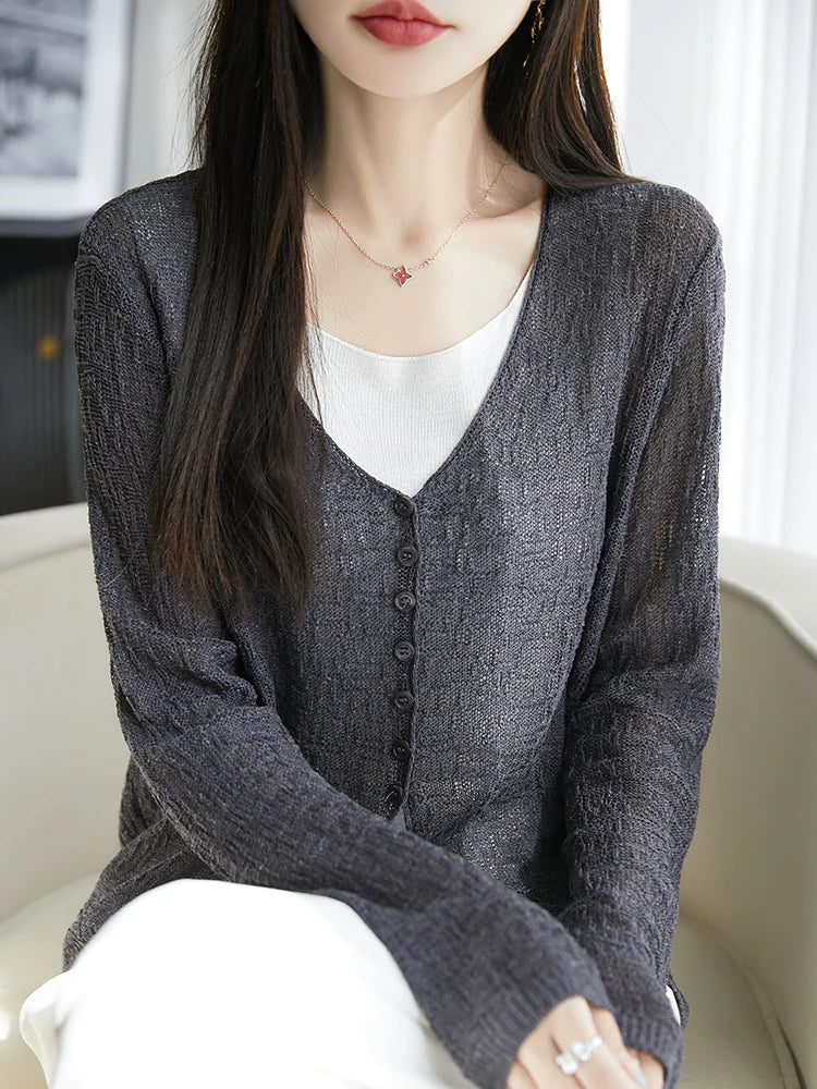 Woman wearing a gray cardigan over a white top with a blurred background