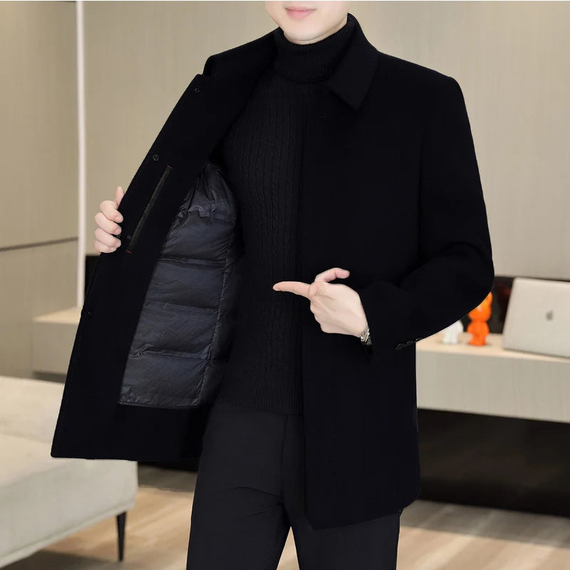 Person wearing a black coat with a puffer vest, standing indoors.