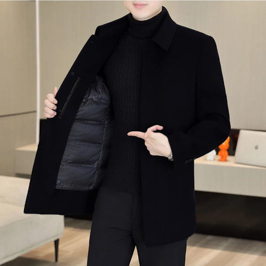 Person wearing a black coat with a puffer vest, standing indoors.