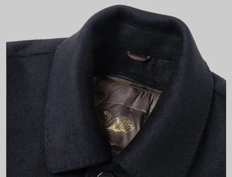 Close-up of a dark coat with a collar and embroidered detail on a white background