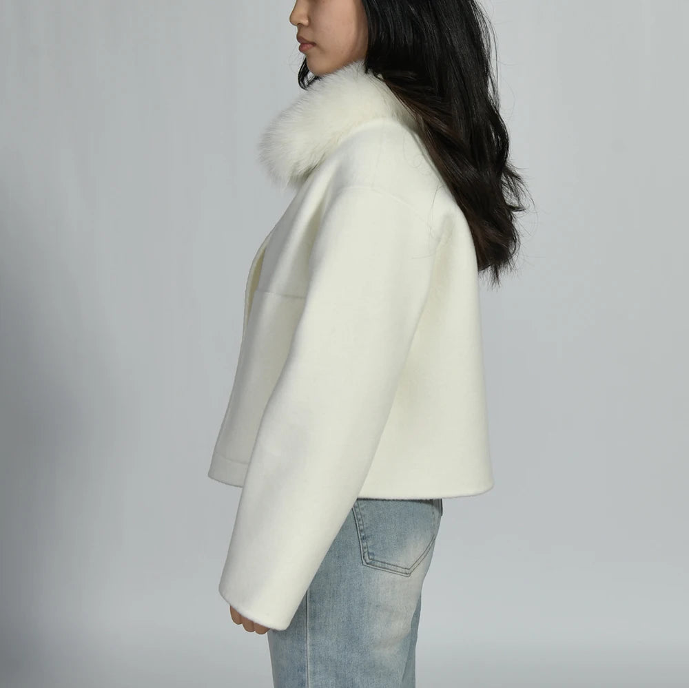 Person wearing a white coat with fur collar against a plain background