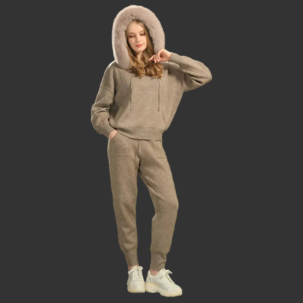 Woman wearing a beige tracksuit with a hood against a gray background