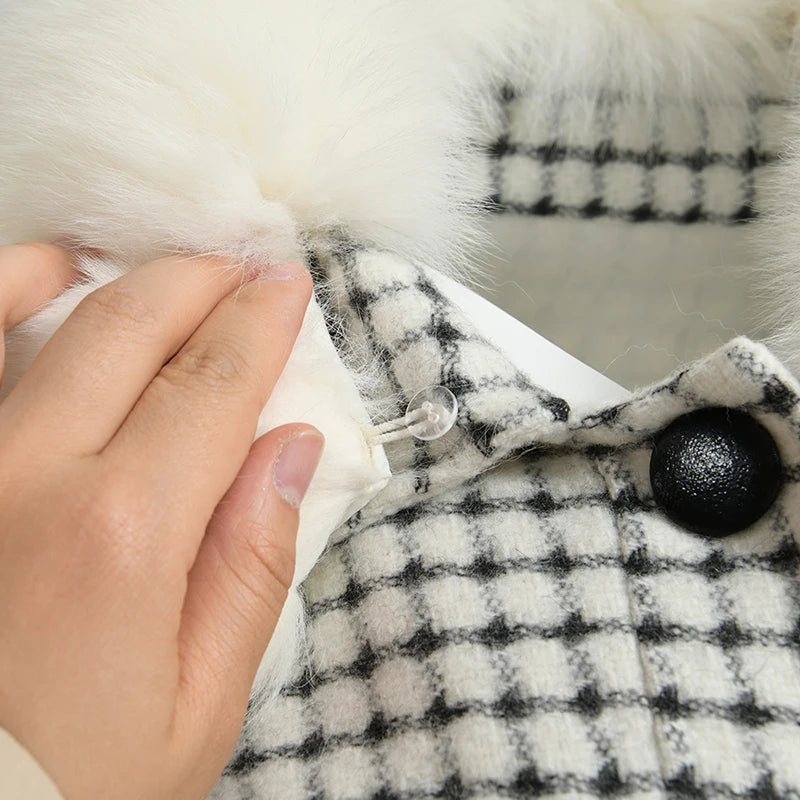 Close-up of a hand holding a checkered fabric with a fluffy white trim, featuring the brand 'Bella'.