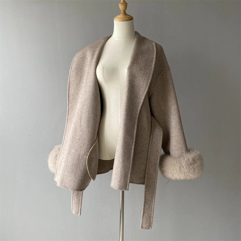 Beige shrug with fur trim on a mannequin against a gray background