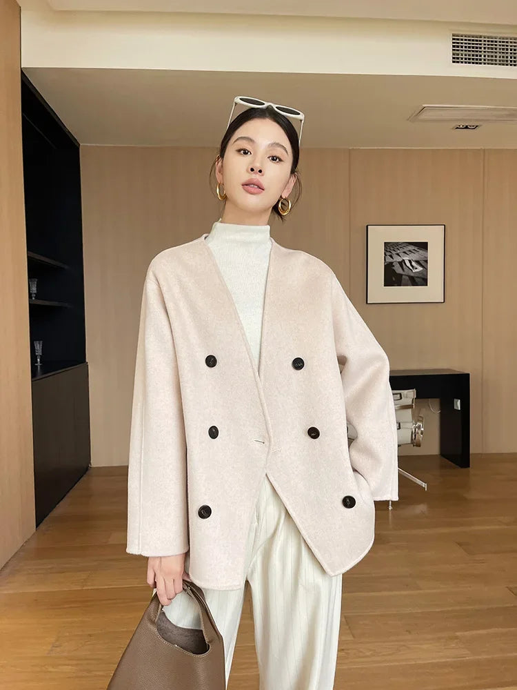 Woman wearing a light pink blazer with black buttons in an indoor setting