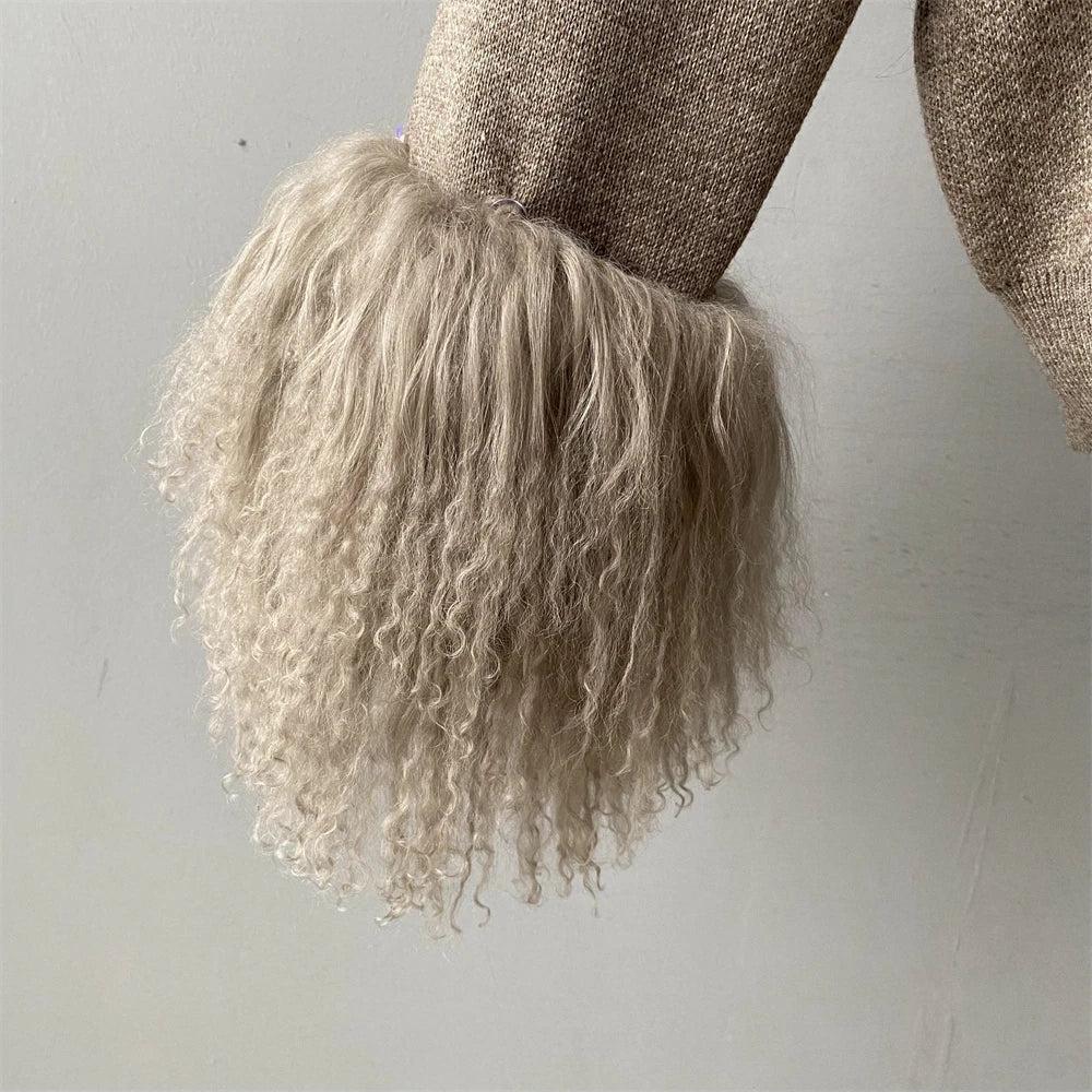 Close-up of a person wearing a textured sweater with a fluffy beige hood against a light background