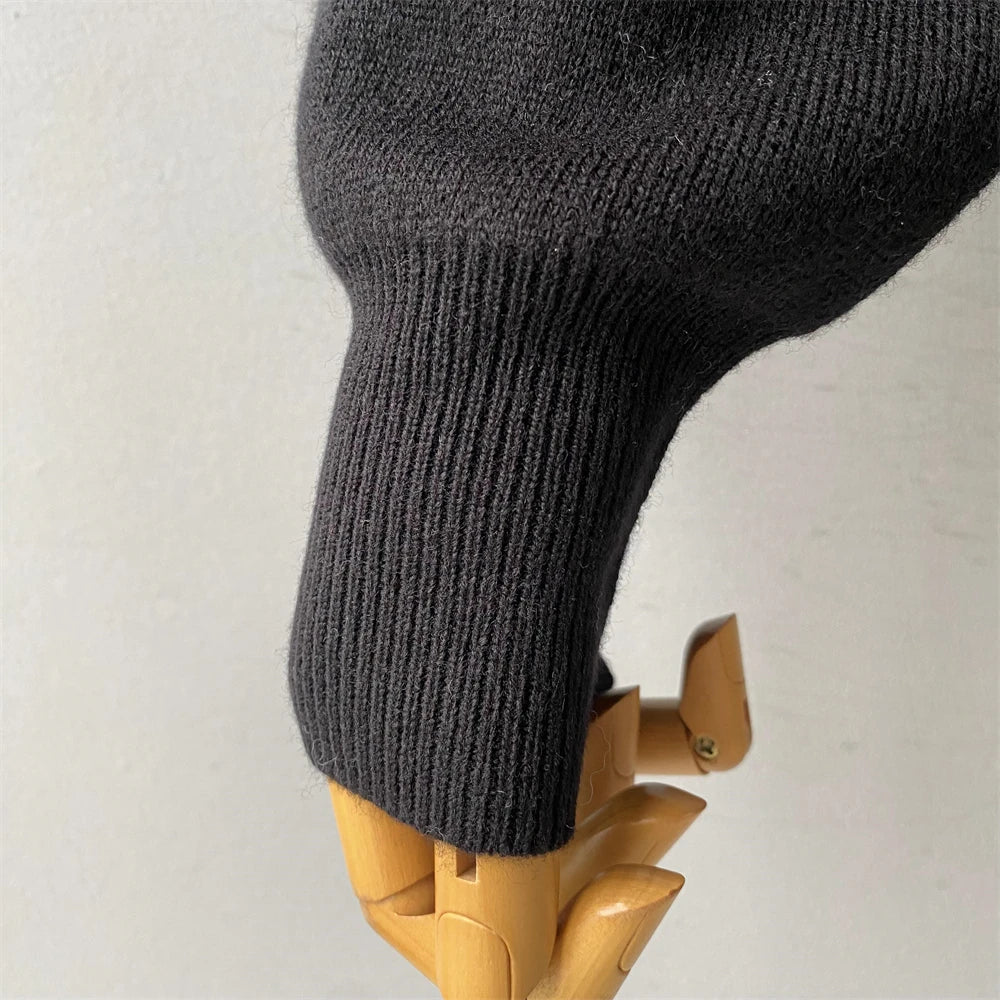 Dark gray knit sweater on a wooden mannequin against a light background