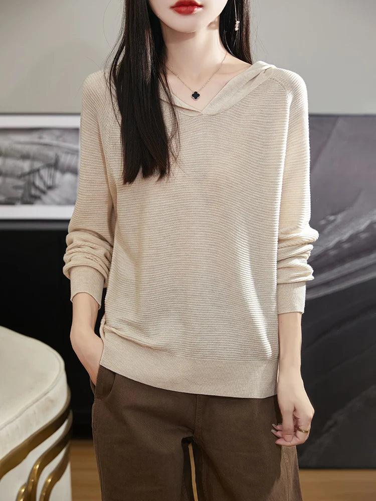 Person wearing a beige sweater and brown pants in an indoor setting